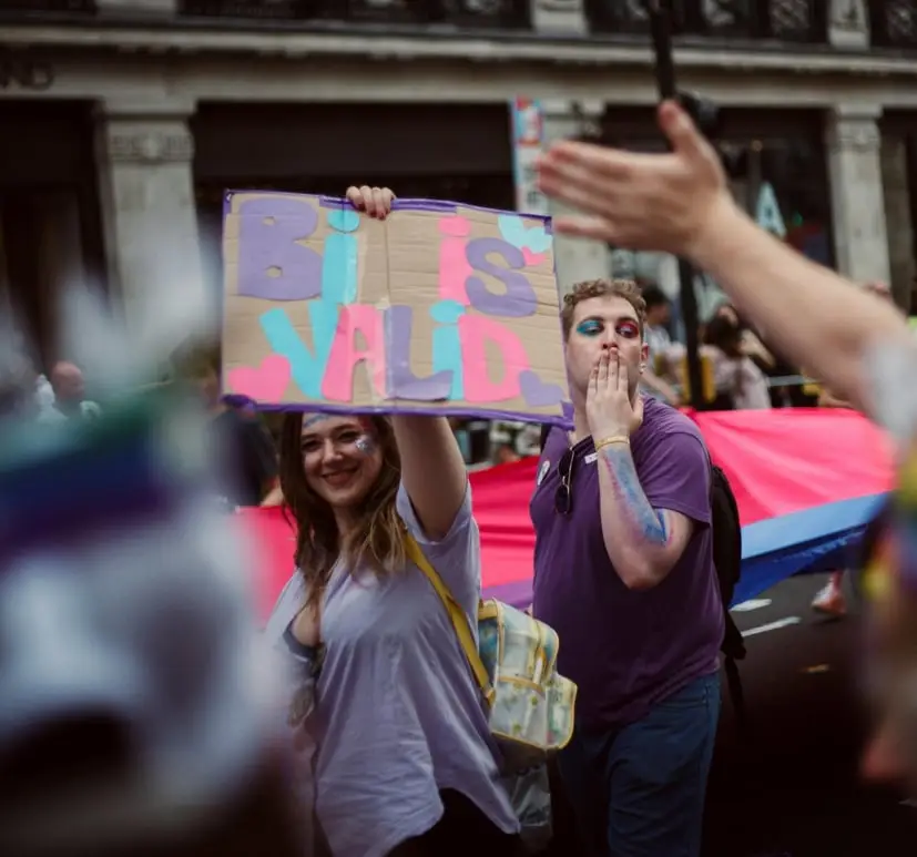 a woman and man at pride even holding bi is valid sign