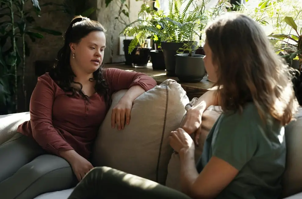 a woman sitting on a couch talking to another woman