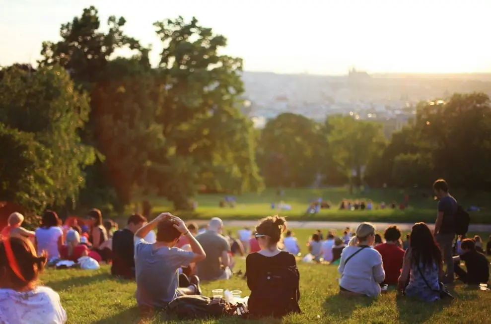 a crowd seated on the grass in a park socializing