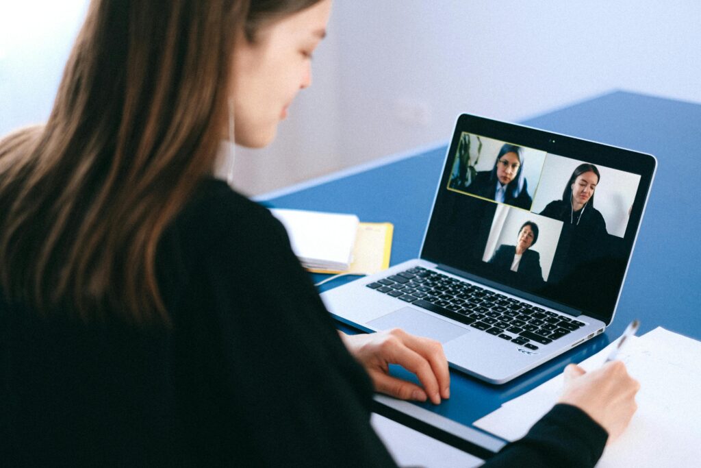 woman facing an open laptop with three people on screen in a zoom meeting