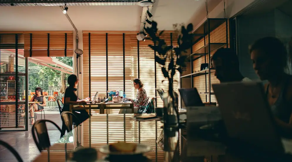 people seated at a cage with laptops and coffee