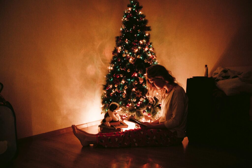 A woman sitting and reading in front of the christmas tree