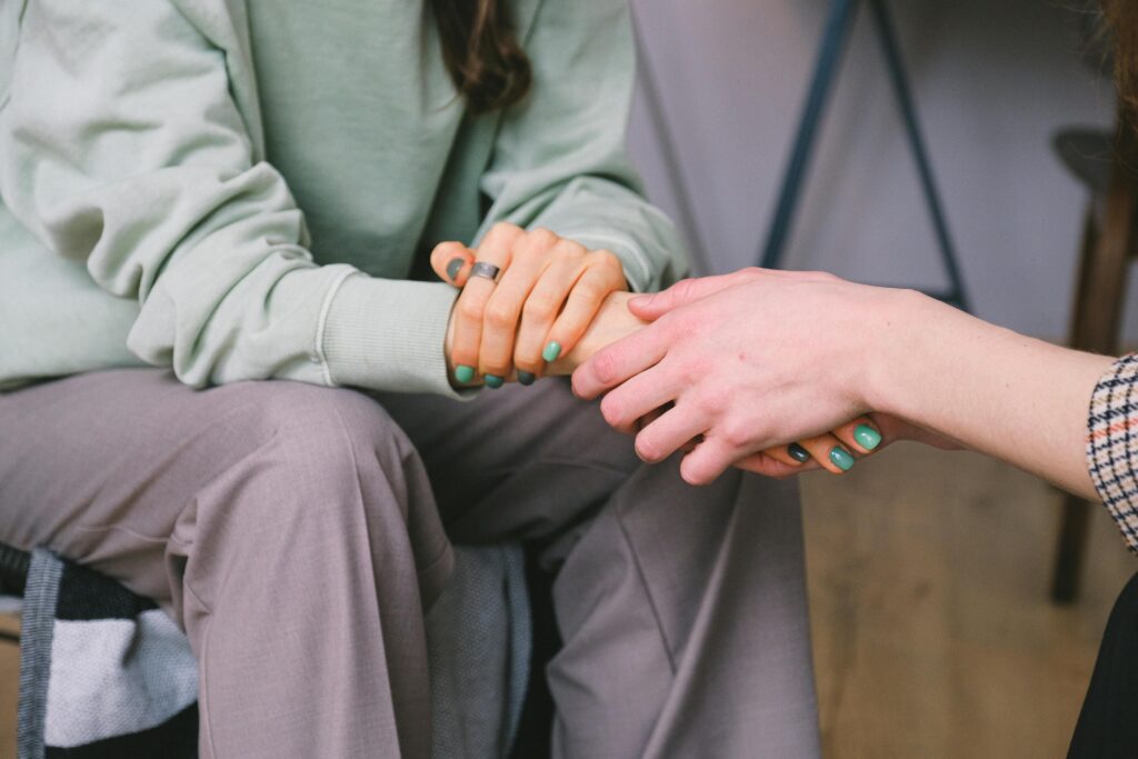 A close up of two people sitting across from each other holding hands