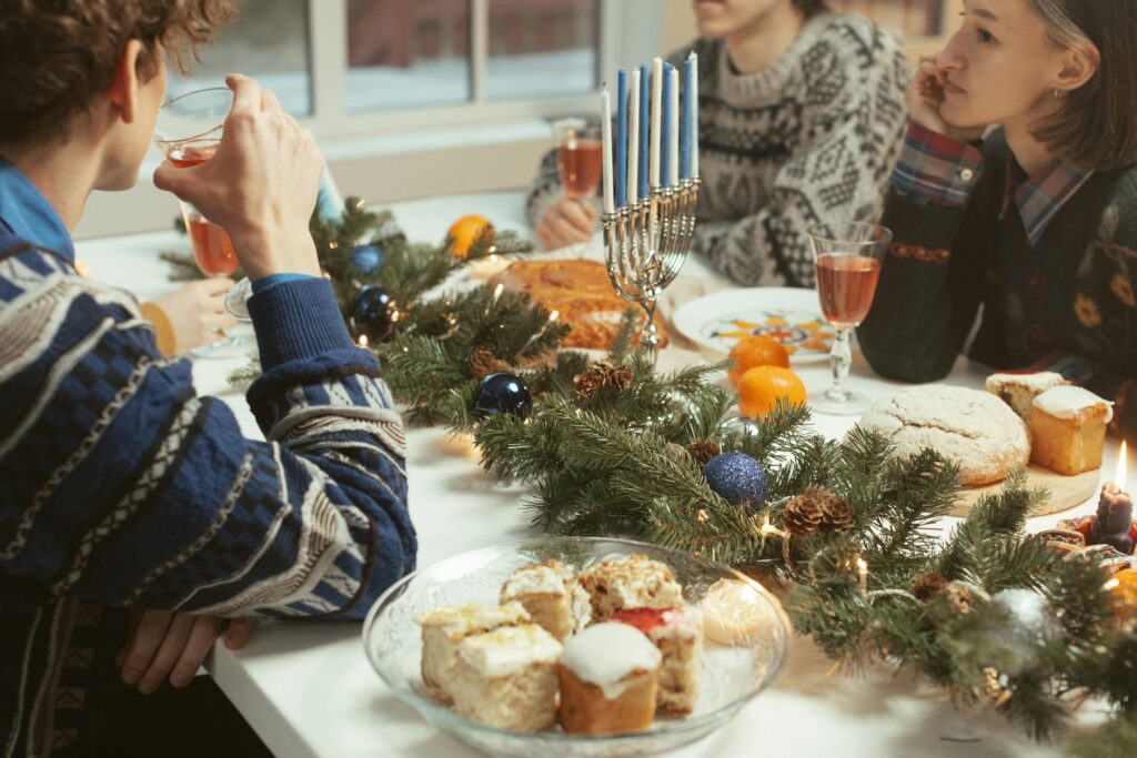 A table of three people with a Hanukkah table setting eating food and drinking rose. 